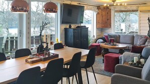 Un espace de vie moderne comprenant un coin repas, un ensemble de canapés et un téléviseur fixé au mur.