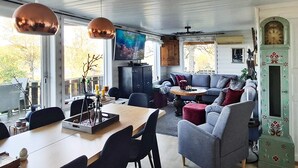 Un salon moderne comprenant un coin repas, un téléviseur et une horloge décorative.