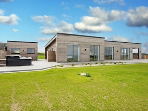 A modern two-story building with large sliding glass doors and a patio area with a hot tub. - 5 Star Holiday Home in Lemvig (Lemvig)