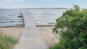 A wooden pier leading to a body of water with a distant view of land and a tall structure. - 5 Star Holiday Home in Lemvig (Lemvig)