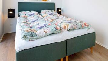 A bed with a floral duvet, two bedside lamps, and a window with a view.