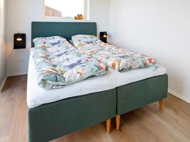 Una cama con edredón floral, dos lámparas de noche y una ventana con vistas.
