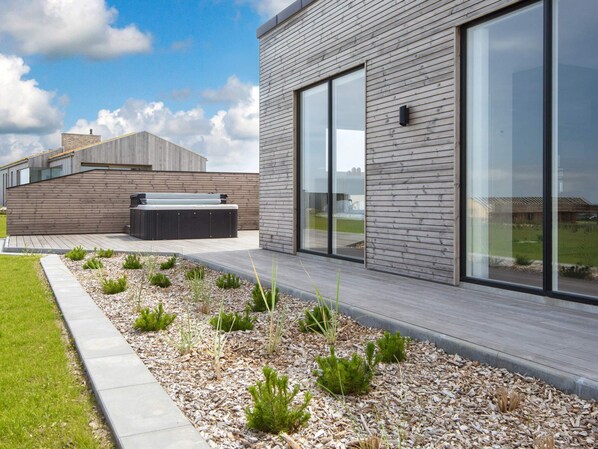 A modern building with a wooden exterior, large windows, and a landscaped garden area.