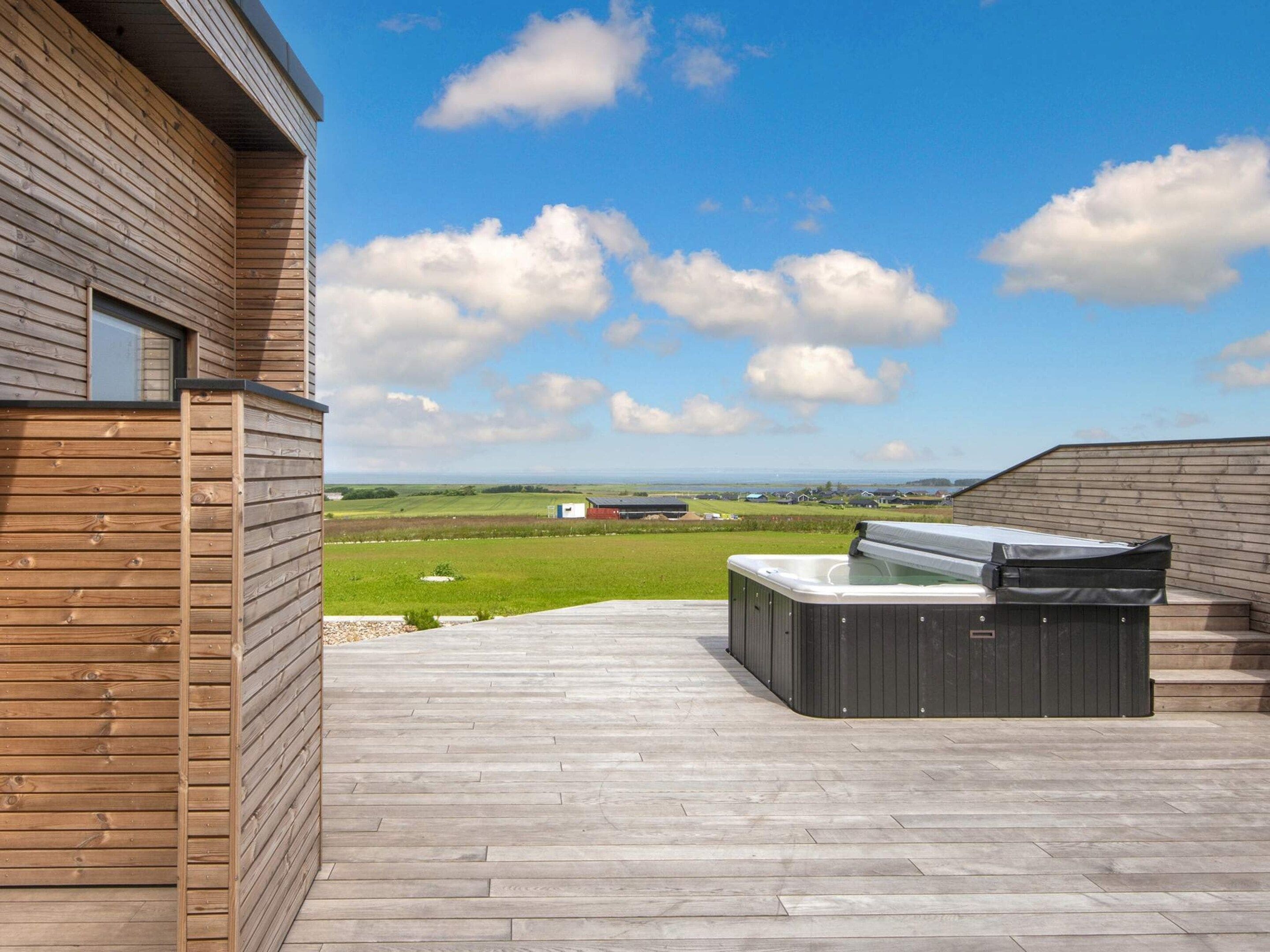 A wooden deck with a hot tub and a view of the countryside.