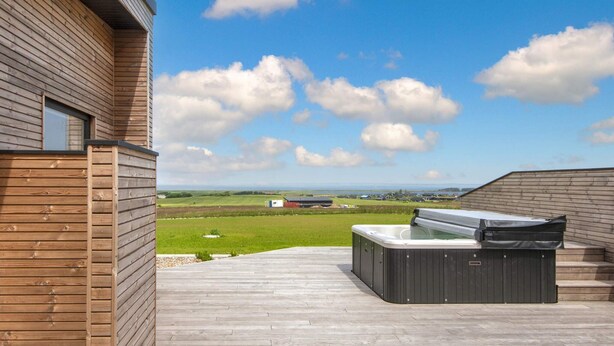A wooden deck with a hot tub and a view of the countryside. - 5 Star Holiday Home in Lemvig (Lemvig)