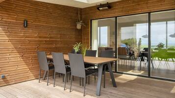 A modern dining area with a wooden wall, a large table, and chairs.