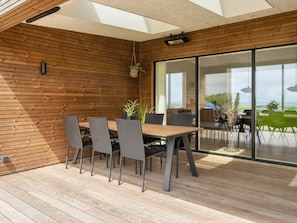 A modern dining area with a wooden wall, a large table, and chairs. - 5 Star Holiday Home in Lemvig (Lemvig)