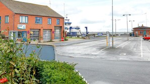 Un bâtiment situé sur la côte, avec une façade en briques rouges, une enseigne bleue et une vue dégagée sur la mer.