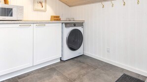 A laundry room with a washing machine, cabinets, a microwave, and a wooden ceiling. - 4 Star Holiday Home in Ansager (Ansager)