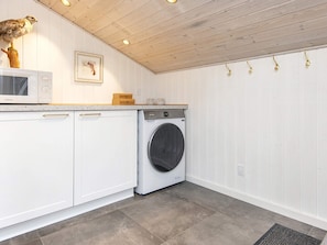 A laundry room with a washing machine, cabinets, a microwave, and a wooden ceiling. - 4 Star Holiday Home in Ansager (Ansager)