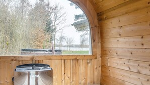 A wooden cabin interior with a built-in sauna, a window overlooking a natural landscape, and a bench. - 4 Star Holiday Home in Ansager (Ansager)