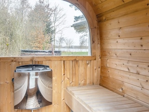L’intérieur d’un chalet en bois comprend un sauna intégré, une fenêtre donnant sur un paysage naturel et un banc.