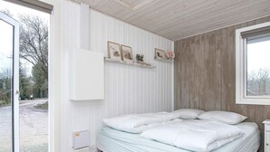 A bedroom with a bed, a bedside table, a window, and a door leading to an outdoor area. - 4 Star Holiday Home in Ansager (Ansager)