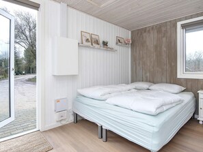 A bedroom with a bed, a bedside table, a window, and a door leading to an outdoor area. - 4 Star Holiday Home in Ansager (Ansager)