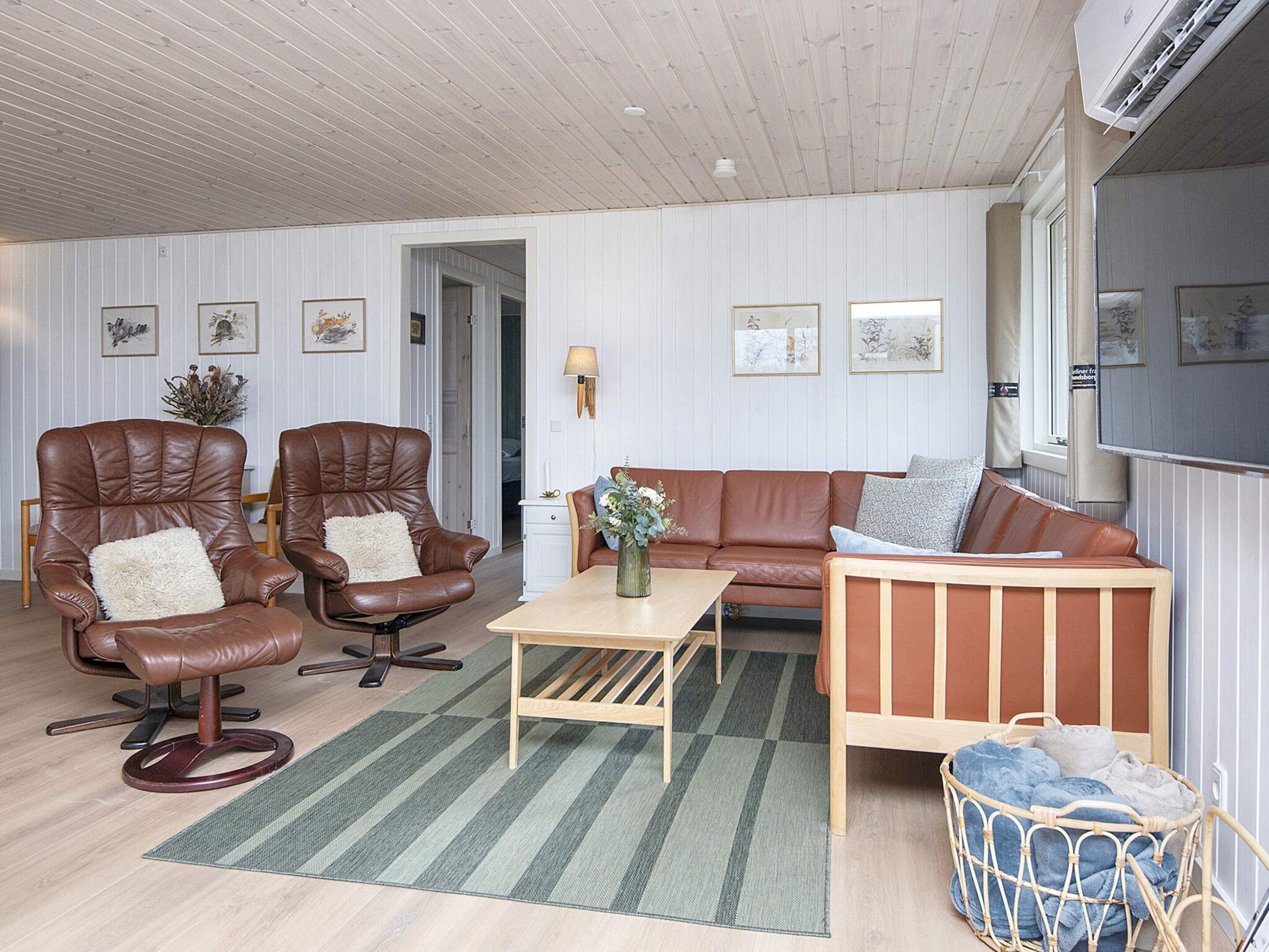 A room with two leather armchairs, a wooden sofa, a small table, and a wicker basket.