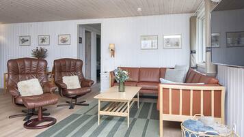 A room with two leather armchairs, a wooden sofa, a small table, and a wicker basket.
