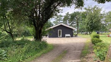 A gravel path leading to a small building with a door and a bench outside.