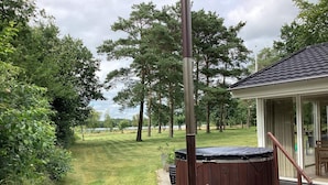 A hot tub with a wooden ladder, a metal pole, and a grassy yard with trees. - 4 Star Holiday Home in Ansager (Ansager)