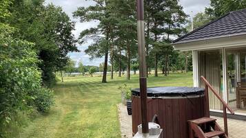 A hot tub with a wooden ladder, a metal pole, and a grassy yard with trees.