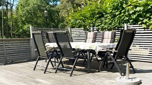 An outdoor patio with a wooden deck, a table with chairs, and a fence in the background. - 4 Star Holiday Home in Laholm-by Traum (Laholm)