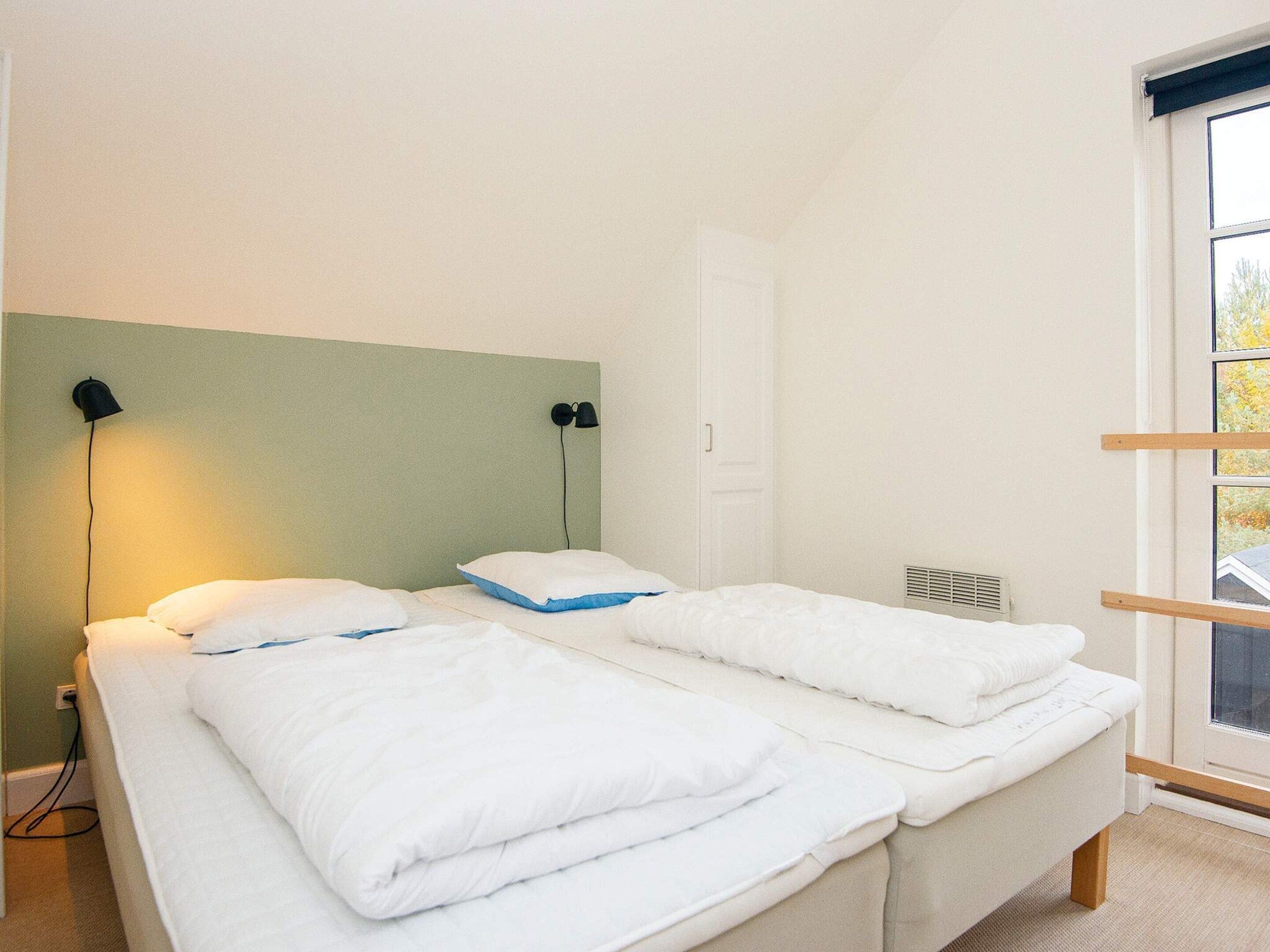 Una habitación con dos camas, un ventanal y una puerta.
