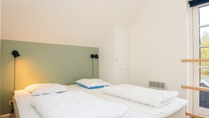 Une chambre avec deux lits, une fenêtre donnant sur un beau paysage et une porte.