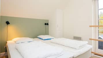 Una habitación con dos camas, un ventanal y una puerta.