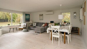 A spacious living area with a sofa, dining table, and chairs, a window with a view of the outdoors, and a ceiling with exposed beams. - 6 Person Holiday Home in Hojby (Hojby)