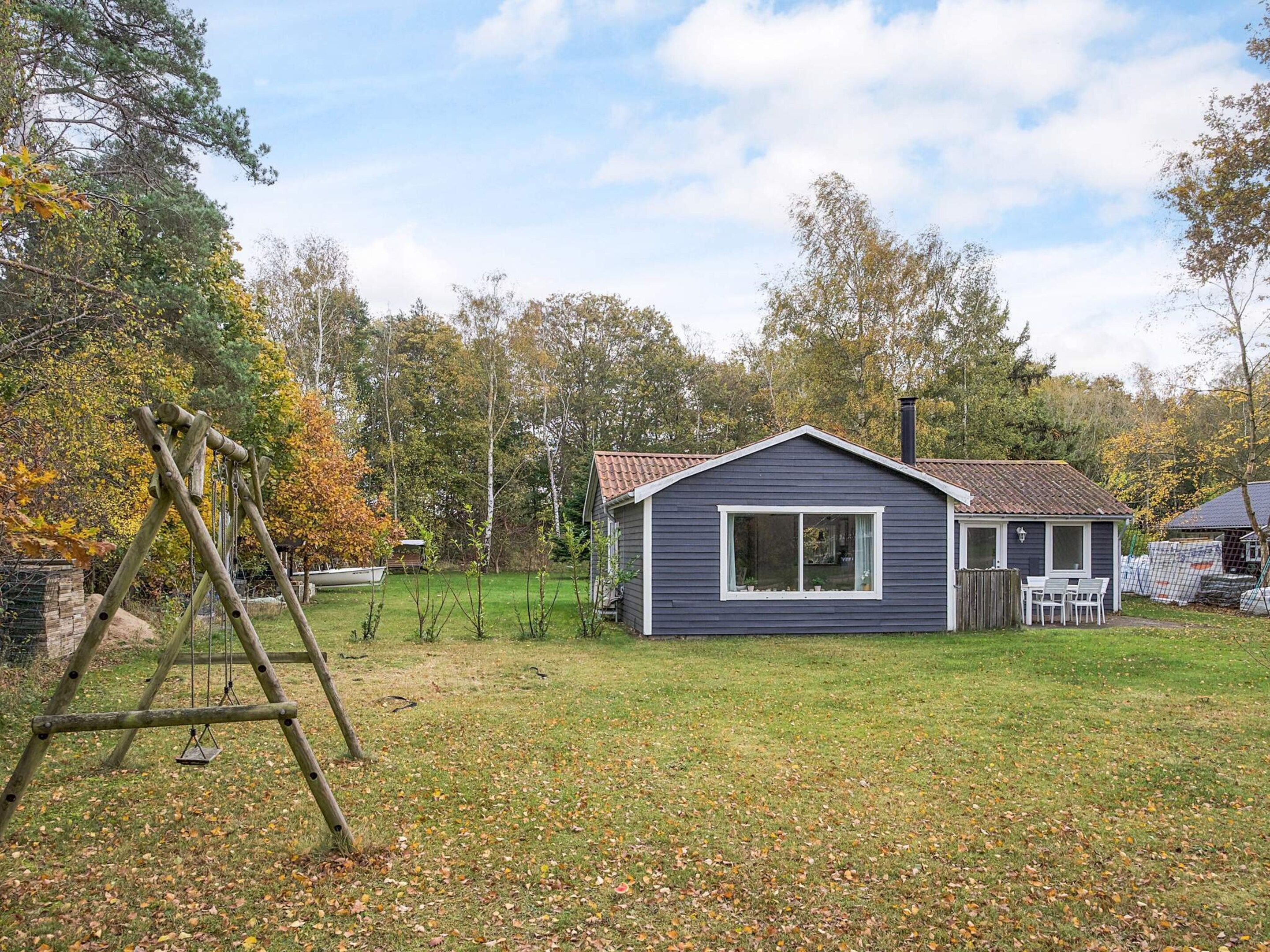 A small, single-story cabin with a dark exterior, a large window, and a chimney.
