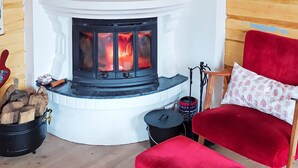 A cozy room with a fireplace, a red chair, and a small table.