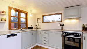 Une cuisine moderne avec des meubles blancs, un lave-vaisselle encastré, un four en acier inoxydable et un plancher en bois.