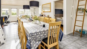 A spacious dining area with a long table, wooden chairs, and hanging pendant lights. - 5 Star Holiday Home in Hals (Hals)
