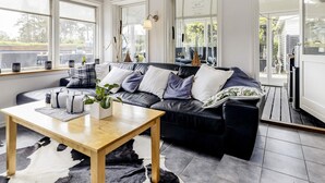 A modern living room with a black leather sofa, a wooden coffee table, and a cowhide rug. - 5 Star Holiday Home in Hals (Hals)