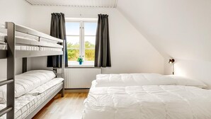 Une chambre de dortoir avec des lits superposés, une fenêtre avec des rideaux, une lampe de chevet et une vue sur la verdure à l’extérieur.