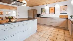Une cuisine moderne dotée d’un îlot central, de meubles blancs et de luminaires suspendus.