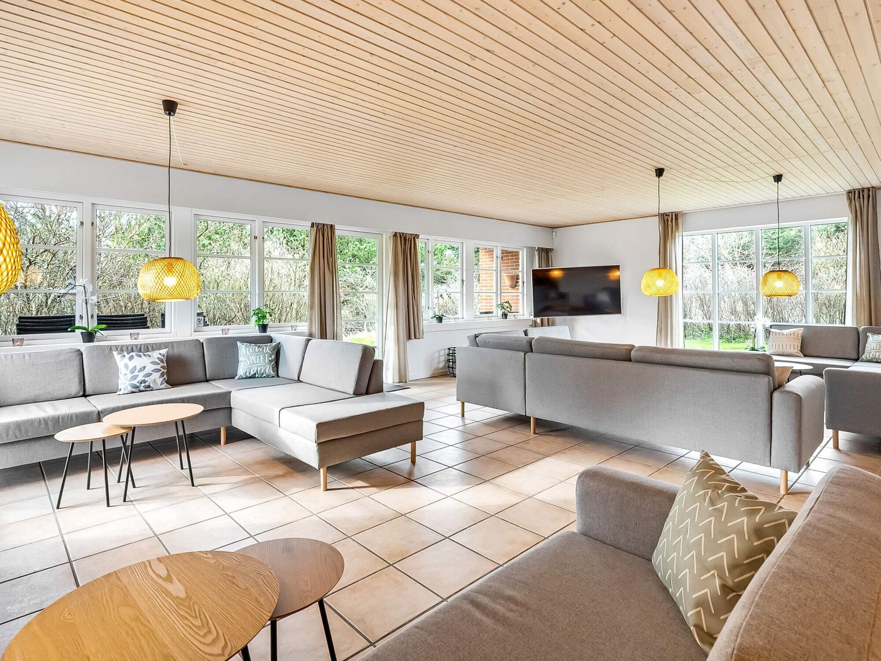 En moderne stue med en hjørnesofa, et sofabord og et fjernsyn monteret på væggen.