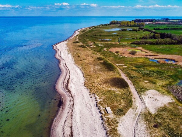 An aerial view of a coastal area with a beach, a dirt path, and green fields. - 4 Star Holiday Home in Nordborg (Nordborg)