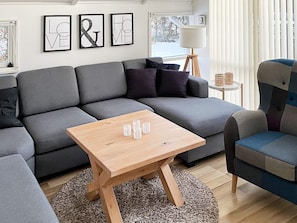 A modern living room with a grey sectional sofa, a wooden coffee table, and a patterned rug. - 4 Star Holiday Home in Nordborg (Nordborg)