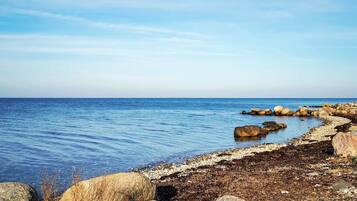 Eine Küstenlandschaft mit felsiger Uferlinie, ruhiger See und blauem Himmel.