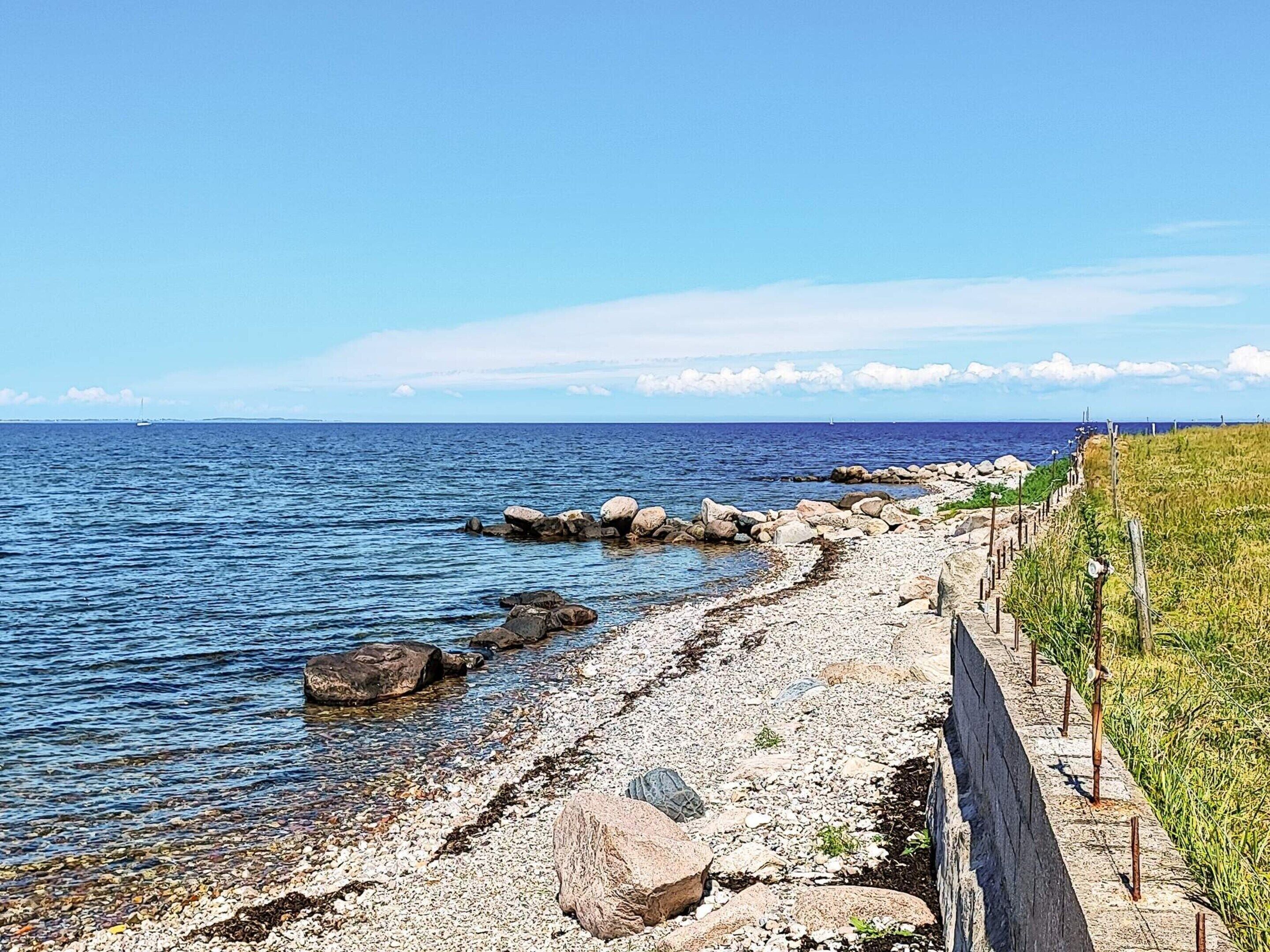 A rocky shoreline with a clear view of the sea and a distant boat.