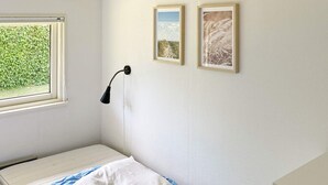 A small, single-bed room with a window, a bedside lamp, and two framed pictures on the wall. - 4 Star Holiday Home in Nordborg (Nordborg)