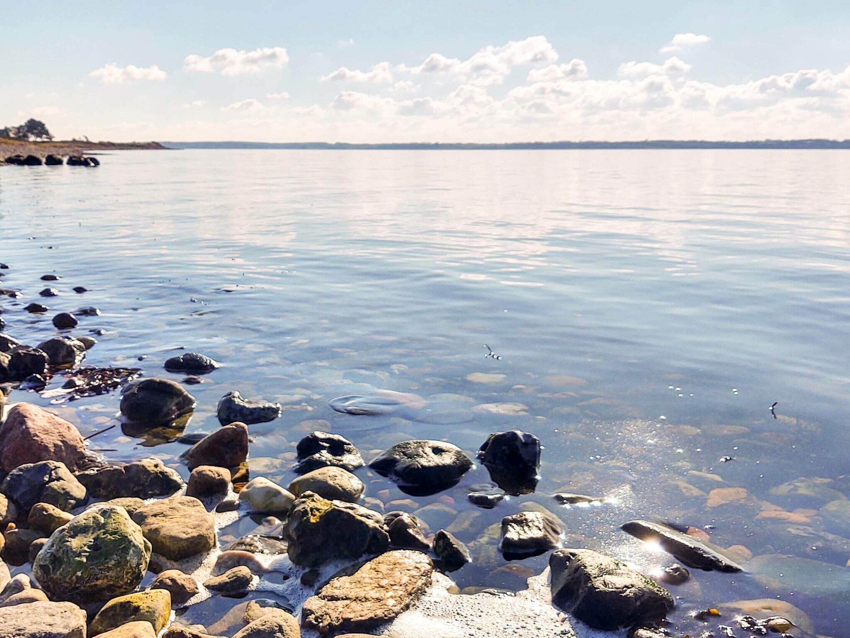 Un lago tranquilo con aguas cristalinas, rodeado de rocas y piedras pequeñas.