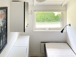 A compact room with a bed, a desk, a window with a view of greenery, and a wall-mounted lamp. - 4 Star Holiday Home in Nordborg (Nordborg)