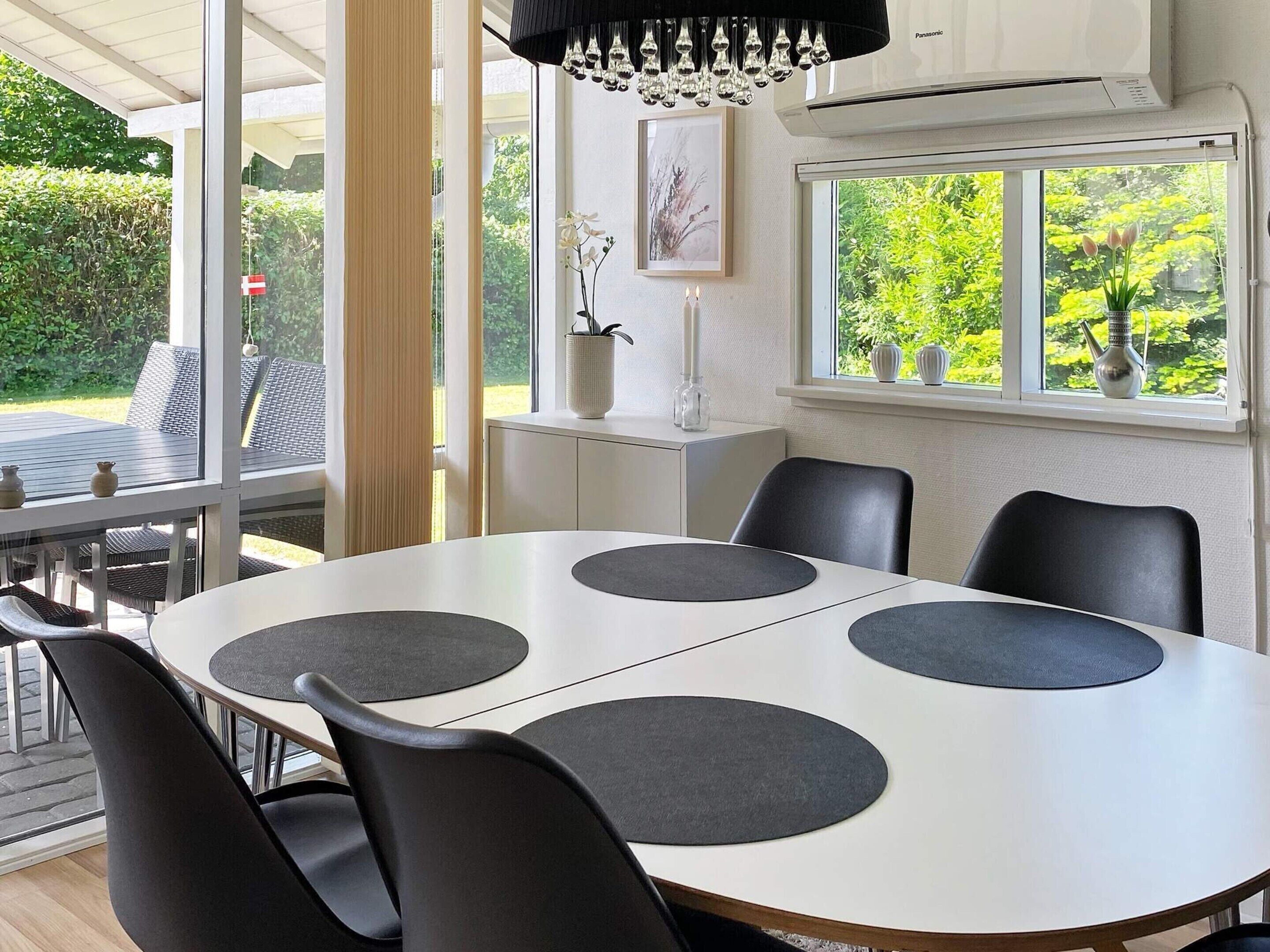 Un comedor moderno con una mesa redonda, sillas negras y vistas a zonas verdes.
