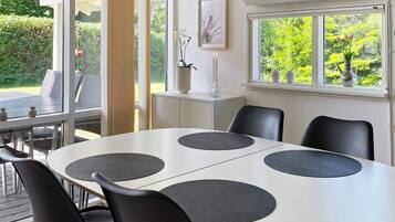 Un comedor moderno con una mesa redonda, sillas negras y vistas a zonas verdes.