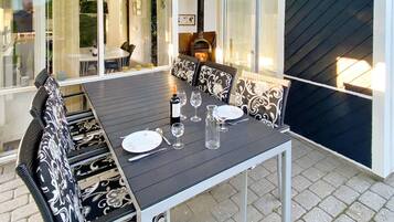 An outdoor dining area with a table set for four, surrounded by patterned chairs.