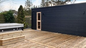 A wooden deck with a built-in barbecue area and a small enclosed space with a door. - 4 Star Holiday Home in Vaeggerlose (Vaeggerlose)
