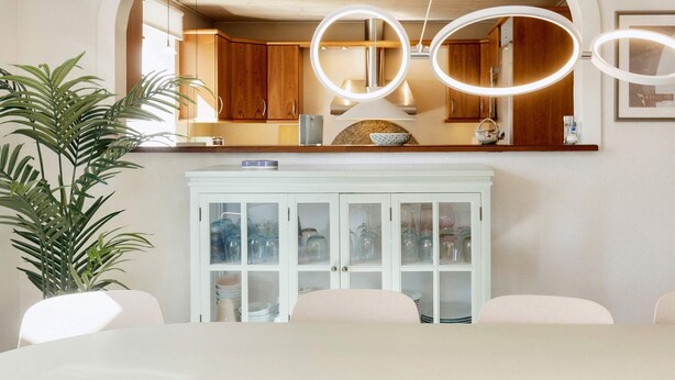A dining area with a white table, chairs, and a cabinet with glass doors. - 4 Star Holiday Home in Vaeggerlose (Vaeggerlose)