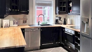 Une cuisine moderne avec des meubles de couleur noire, des appareils électroménagers en acier inoxydable et un plan de travail en bois.