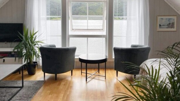 Une pièce chaleureuse avec un plancher en bois, deux fauteuils, une petite table et un téléviseur.